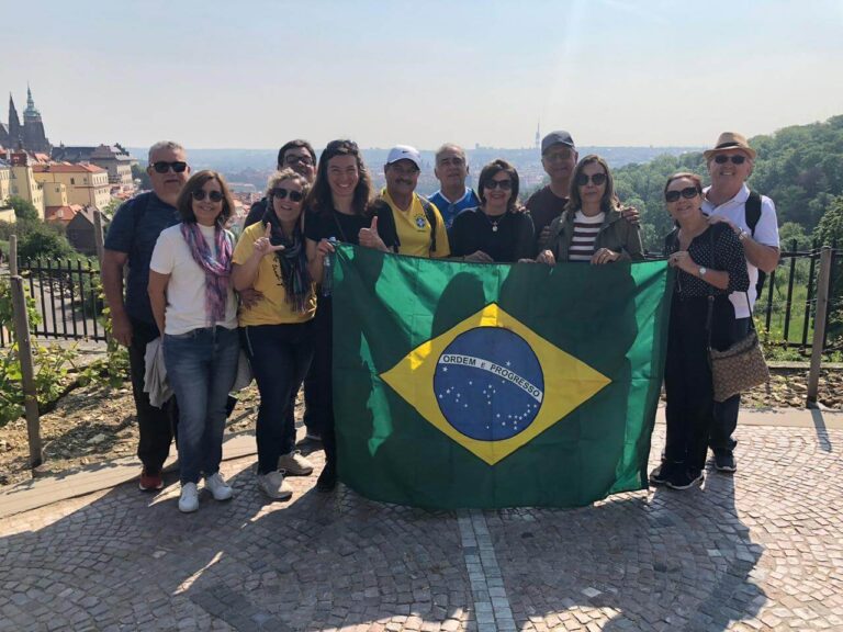 grupo de turistas brasileiros com guia local em Praga segurando bandeira do Brasil